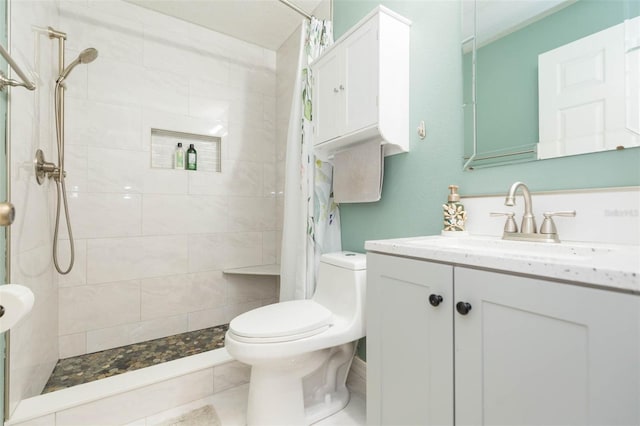 bathroom with toilet, tiled shower, and vanity