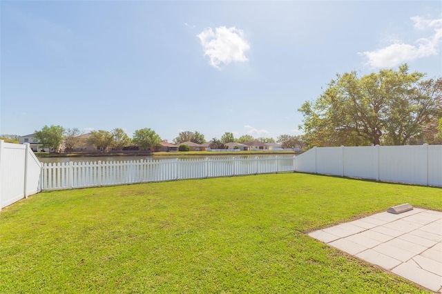 view of yard with a patio, a fenced backyard, and a water view