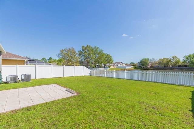 view of yard featuring a water view, central AC, a fenced backyard, and a patio area