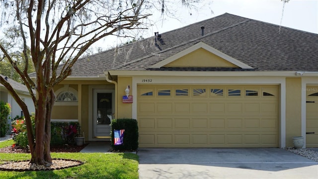 single story home with stucco siding, a garage, driveway, and a shingled roof