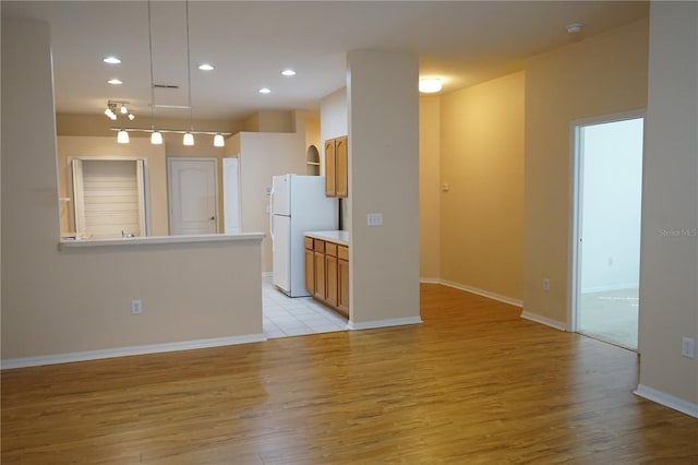 19432 Haskell Pl, Land O Lakes, FL 34638 - kitchen with freestanding refrigerator, light wood-style floors, brown cabinetry, recessed lighting, and decorative light fixtures