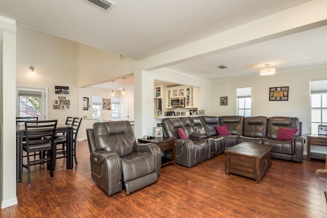 living room featuring dark wood-style floors, a healthy amount of sunlight, and visible vents