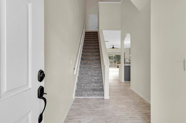 stairway featuring baseboards, arched walkways, and wood finished floors