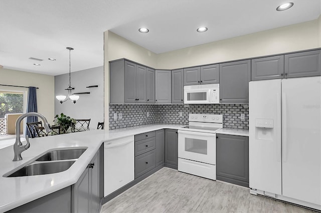 kitchen featuring light countertops, white appliances, a sink, and gray cabinetry