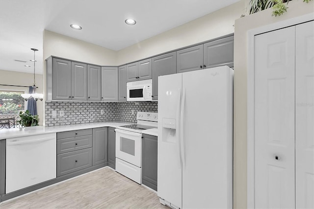 kitchen featuring decorative light fixtures, gray cabinets, light countertops, decorative backsplash, and white appliances
