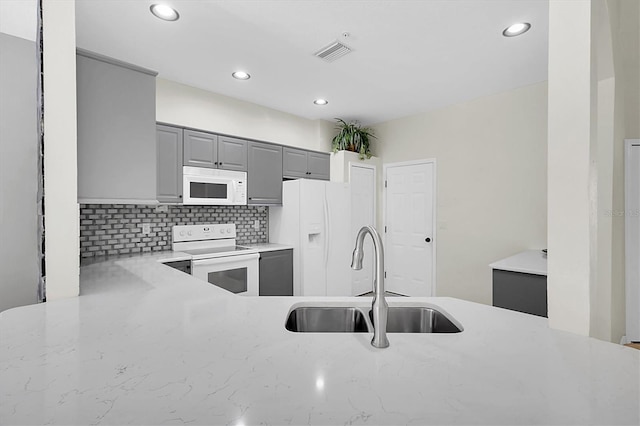 kitchen featuring gray cabinetry, white appliances, a sink, visible vents, and light countertops