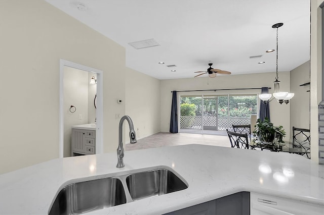 kitchen featuring a ceiling fan, decorative light fixtures, a sink, and light stone countertops
