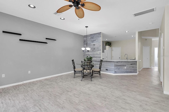 dining area with visible vents, light wood finished floors, baseboards, and ceiling fan with notable chandelier
