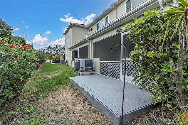 view of home's exterior featuring stucco siding, a lawn, a deck, and central AC unit