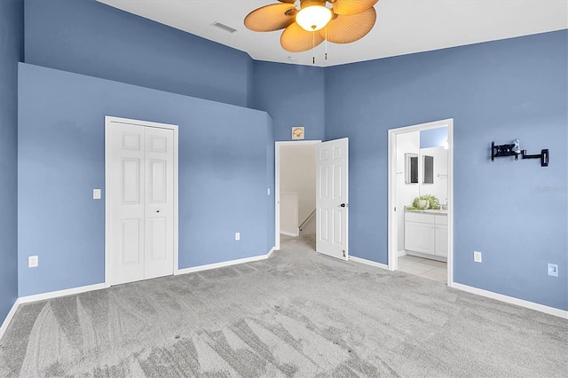 unfurnished bedroom with light colored carpet, visible vents, baseboards, a closet, and ensuite bath