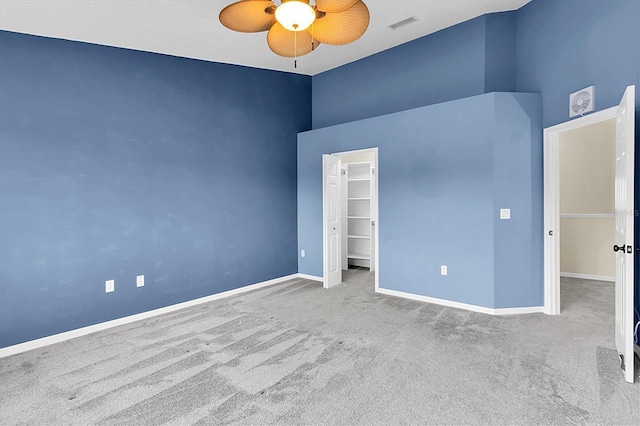 unfurnished bedroom with a walk in closet, a closet, visible vents, light carpet, and baseboards