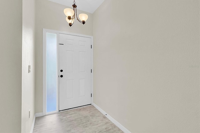 entryway featuring light wood finished floors, baseboards, and a notable chandelier