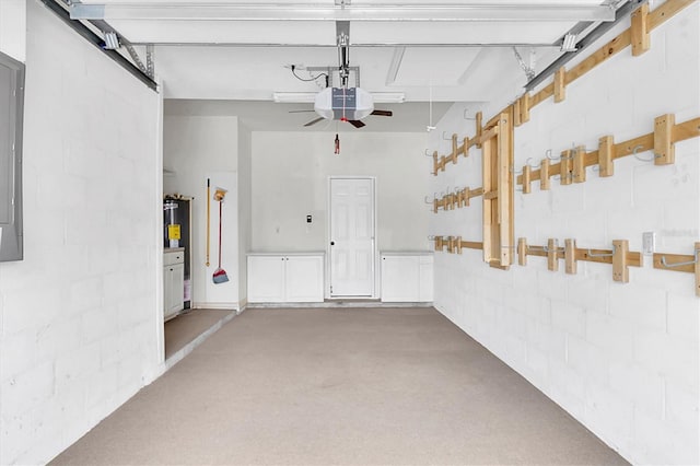 garage featuring electric water heater, concrete block wall, and a garage door opener