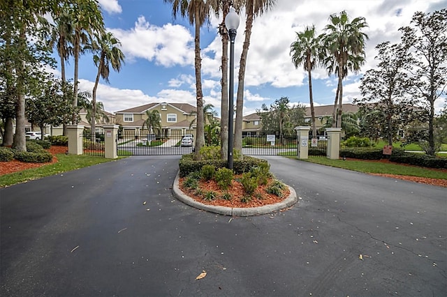 view of road featuring street lights, a gate, a gated entry, a residential view, and curbs