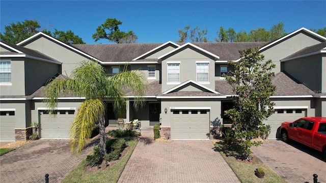 view of front facade featuring driveway, roof with shingles, an attached garage, and stucco siding