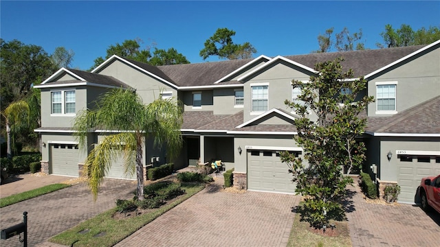 multi unit property with driveway, roof with shingles, an attached garage, and stucco siding