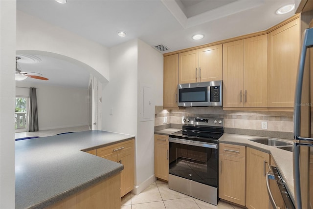 kitchen featuring visible vents, ceiling fan, appliances with stainless steel finishes, light brown cabinetry, and backsplash