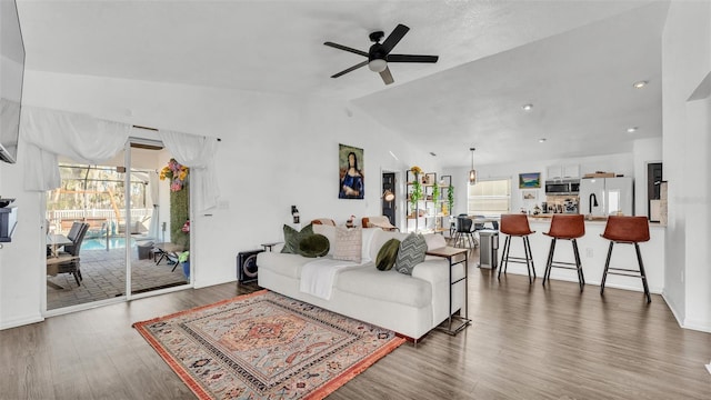 living room featuring hardwood / wood-style floors, vaulted ceiling, and ceiling fan