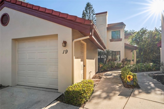 exterior space with driveway, an attached garage, and stucco siding