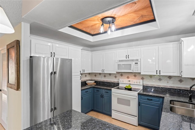 kitchen with blue cabinets, white appliances, a sink, white cabinets, and a raised ceiling