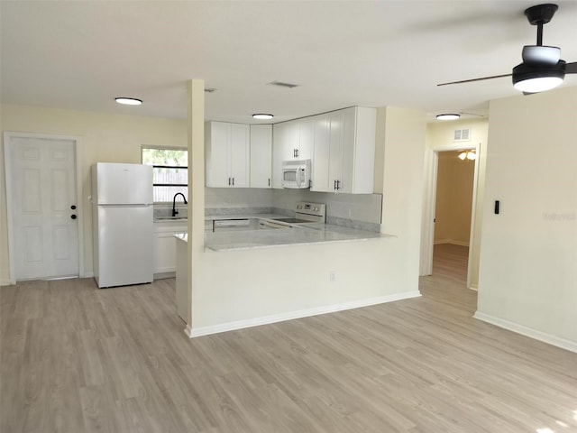 kitchen with visible vents, light countertops, white cabinetry, white appliances, and a peninsula