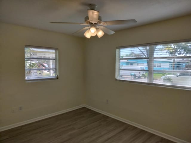 spare room with dark wood-style floors, baseboards, and a ceiling fan