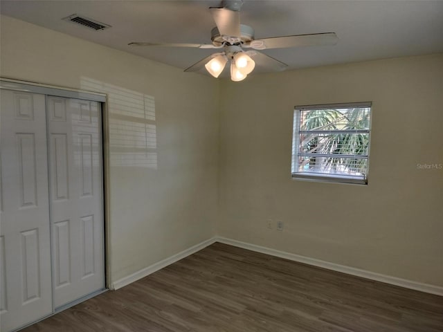 unfurnished bedroom with baseboards, visible vents, dark wood-style floors, ceiling fan, and a closet