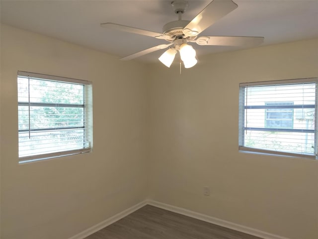 empty room with dark wood-style flooring, plenty of natural light, a ceiling fan, and baseboards