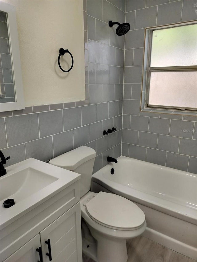 bathroom with tile walls, toilet, washtub / shower combination, vanity, and wood finished floors