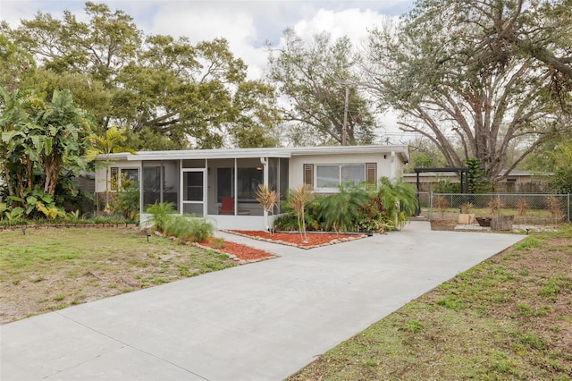 view of front of house with a sunroom, fence, and a front yard