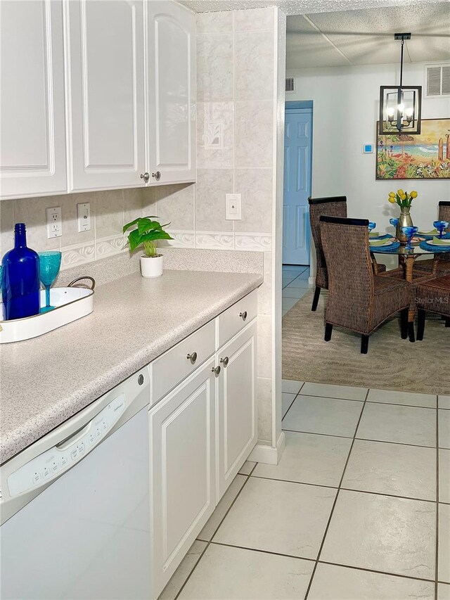 8901 Blind Pass Rd Unit 224, St Pete Beach, FL 33706 - kitchen with white dishwasher, light tile patterned flooring, a chandelier, and white cabinetry