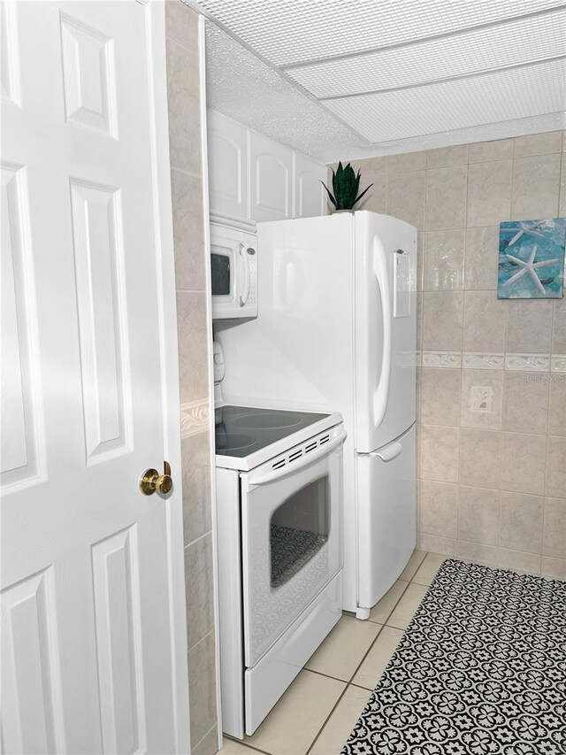 8901 Blind Pass Rd Unit 224, St Pete Beach, FL 33706 - laundry area with tile walls and light tile patterned flooring
