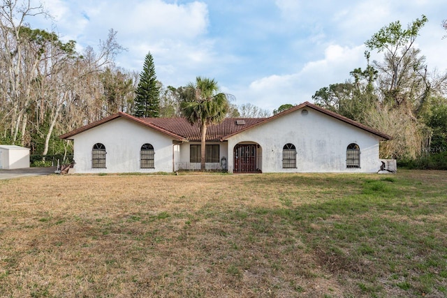 mediterranean / spanish-style home featuring a front lawn, a tile roof, and stucco siding