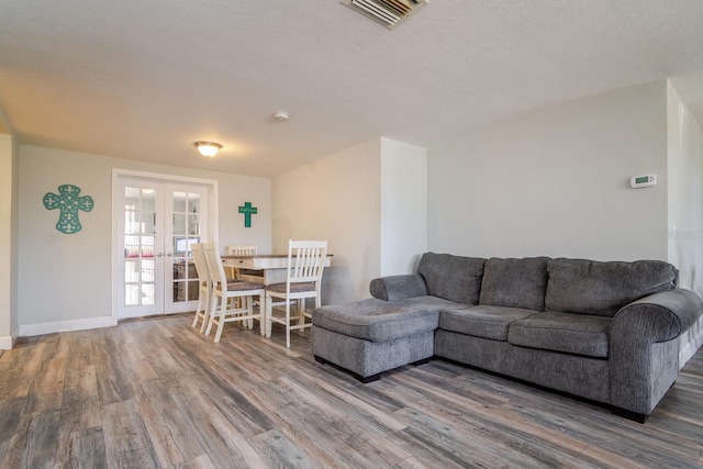 living room featuring french doors, dark wood-type flooring, and a textured ceiling