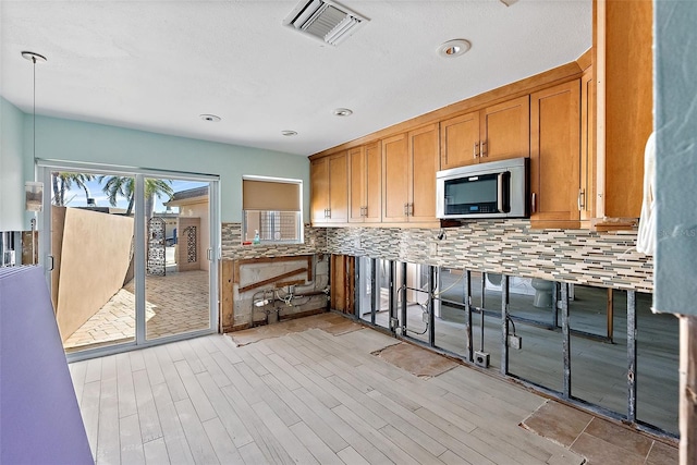 kitchen with hanging light fixtures, light hardwood / wood-style flooring, and decorative backsplash