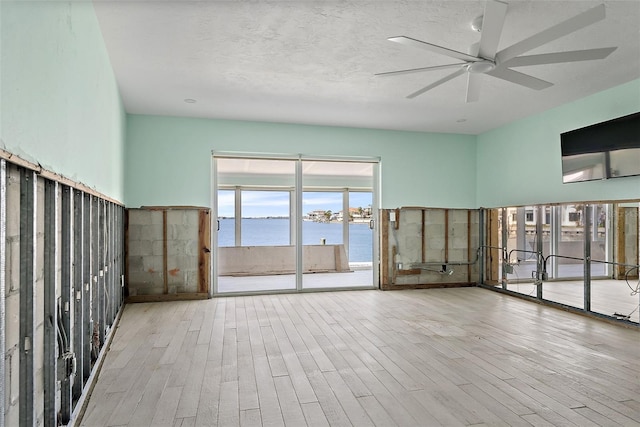 unfurnished room featuring light wood-type flooring, a textured ceiling, and ceiling fan