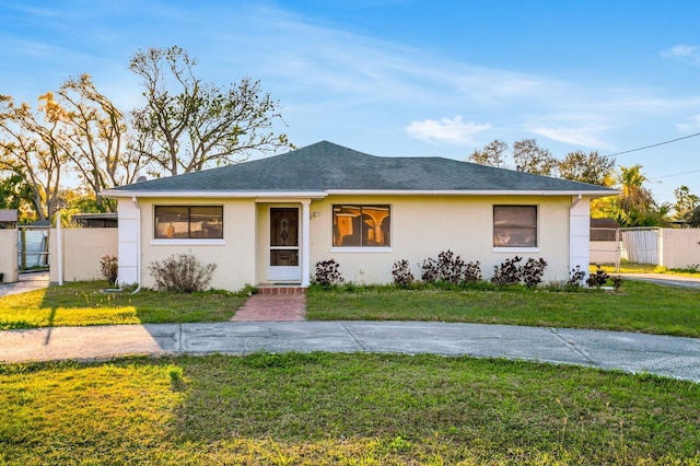 view of front of home featuring a front yard, roof with shingles, fence, and stucco siding