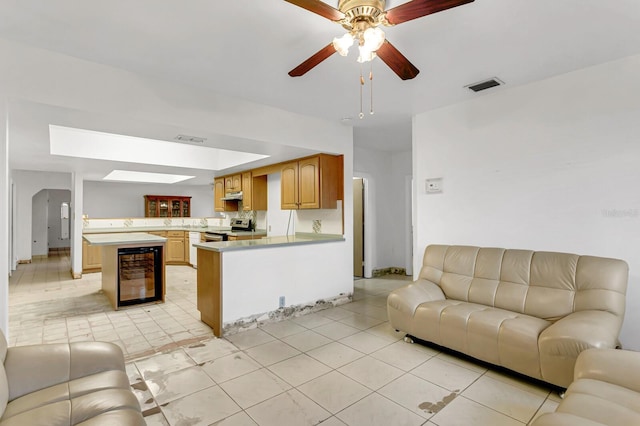 living room featuring light tile patterned floors, ceiling fan, wine cooler, and visible vents