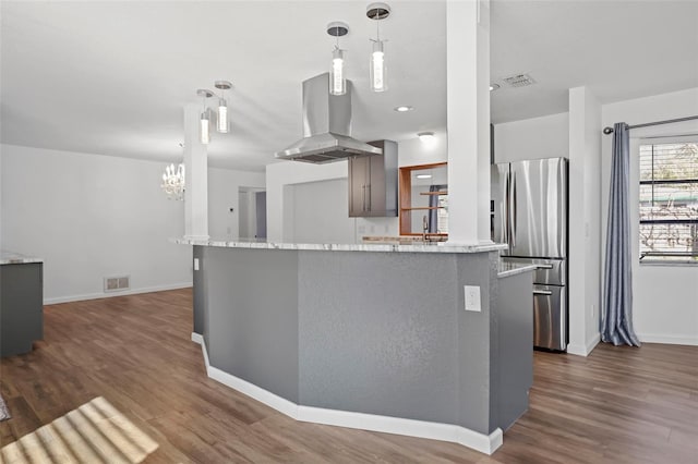 kitchen with island exhaust hood, visible vents, pendant lighting, and stainless steel fridge with ice dispenser