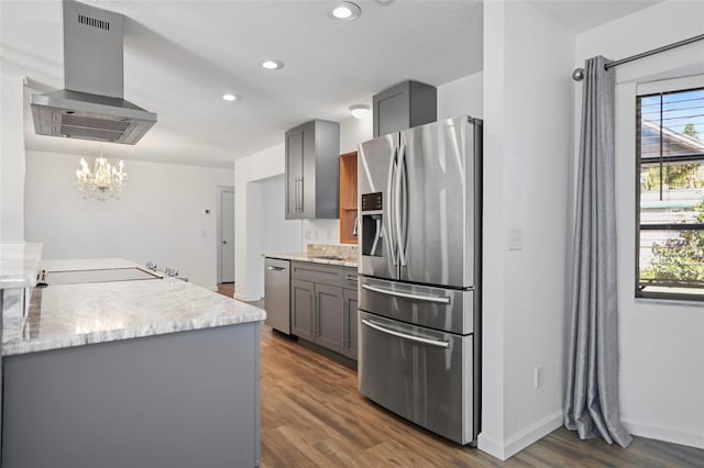 kitchen featuring dark wood finished floors, island exhaust hood, gray cabinets, appliances with stainless steel finishes, and light stone countertops