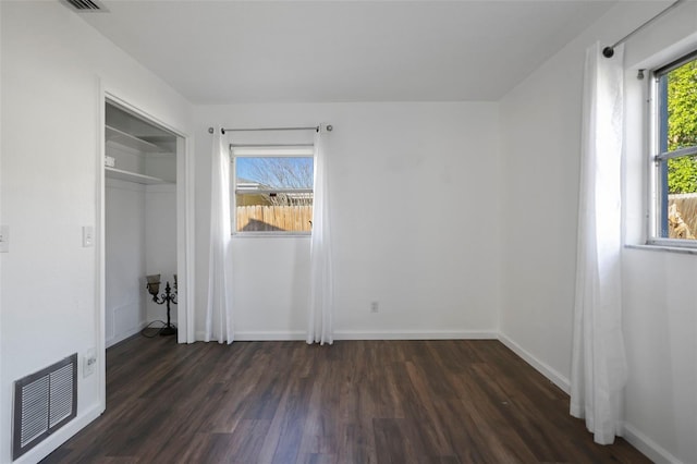 unfurnished bedroom with dark wood-style flooring, a closet, visible vents, and baseboards