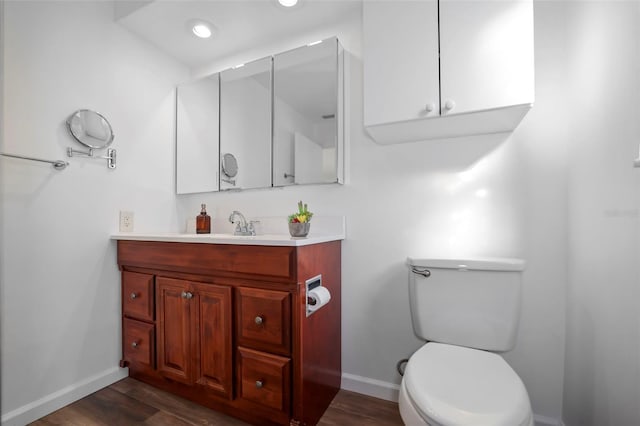 bathroom with baseboards, vanity, toilet, and wood finished floors