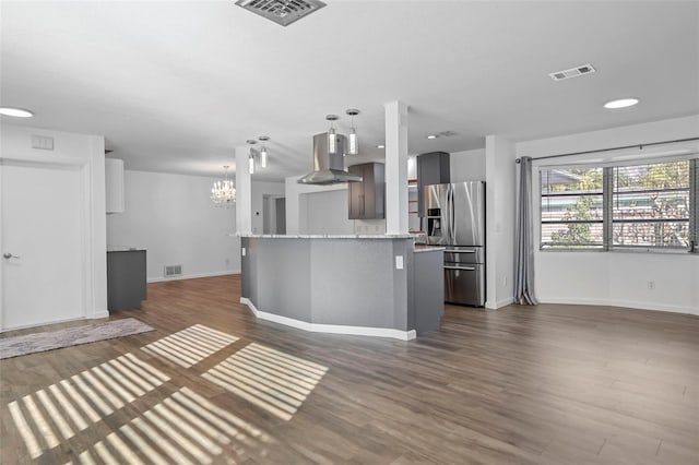 kitchen with dark wood-style floors, stainless steel fridge, island exhaust hood, and visible vents