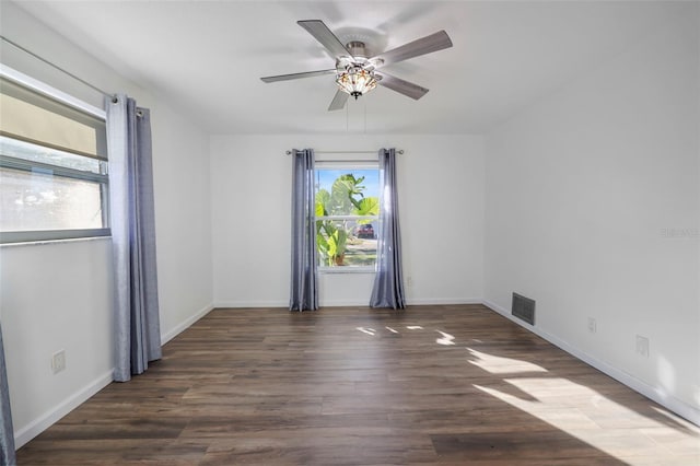 empty room featuring ceiling fan, baseboards, visible vents, and dark wood finished floors