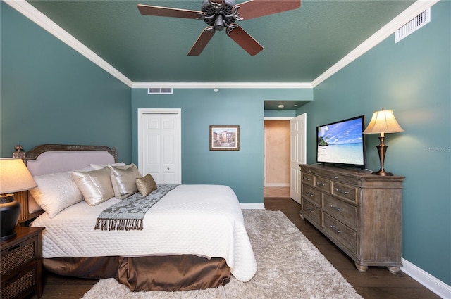 bedroom featuring ceiling fan, a closet, crown molding, and dark wood-type flooring