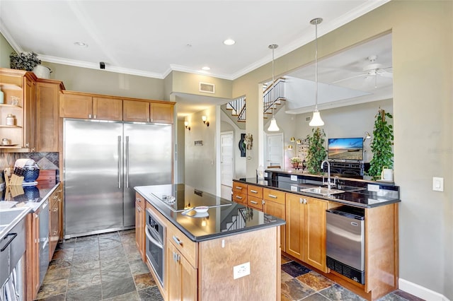 kitchen with stone tile floors, dark countertops, a center island, stainless steel appliances, and a sink