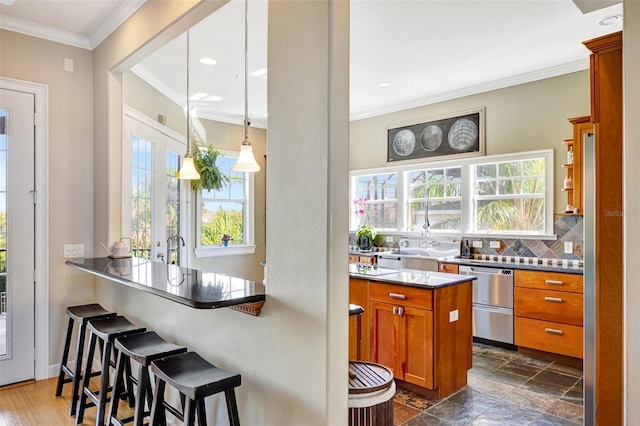 kitchen featuring a breakfast bar, crown molding, brown cabinets, and dishwasher