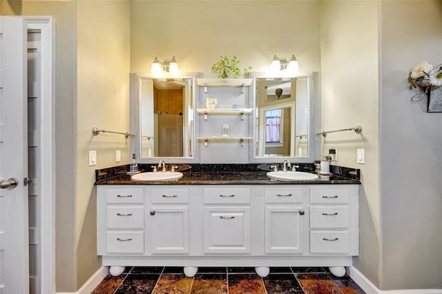 full bath with double vanity, a sink, and baseboards