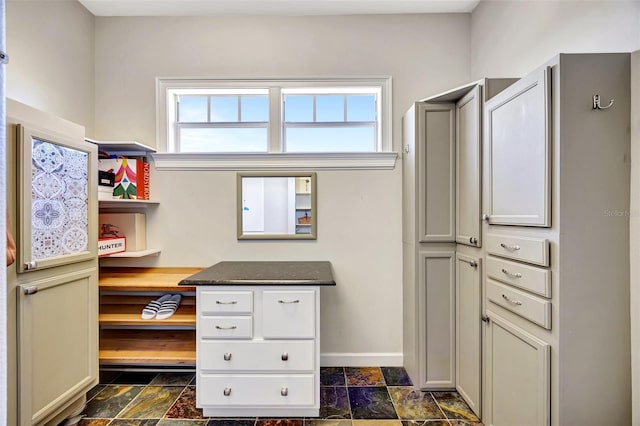 interior space with baseboards and stone tile flooring