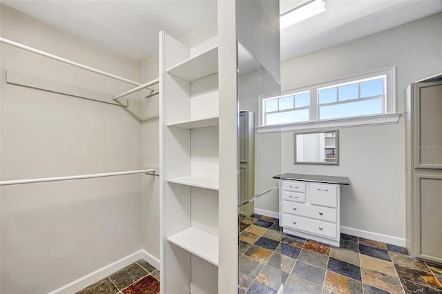 walk in closet featuring stone tile floors